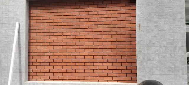 Red brick feature wall framed by grey textured tiles