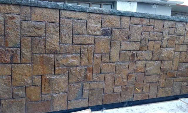 Rust-brown stone wall laid in a mixed-size pattern